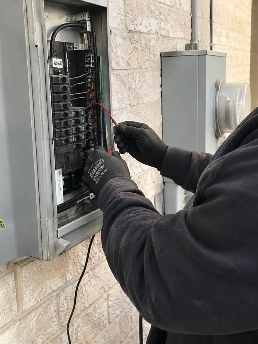 Higher Power Electric electrician landing wires in an outdoor breaker panel beside the meter in Denton